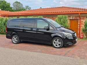 Juodas Mercedes-Benz V-Klasės mikroautobusas pastatytas kieme prie namo,