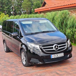 Juodas Mercedes-Benz V-Klasės mikroautobusas pastatytas trinkelių kieme, priekinis vaizdas iš dešinės